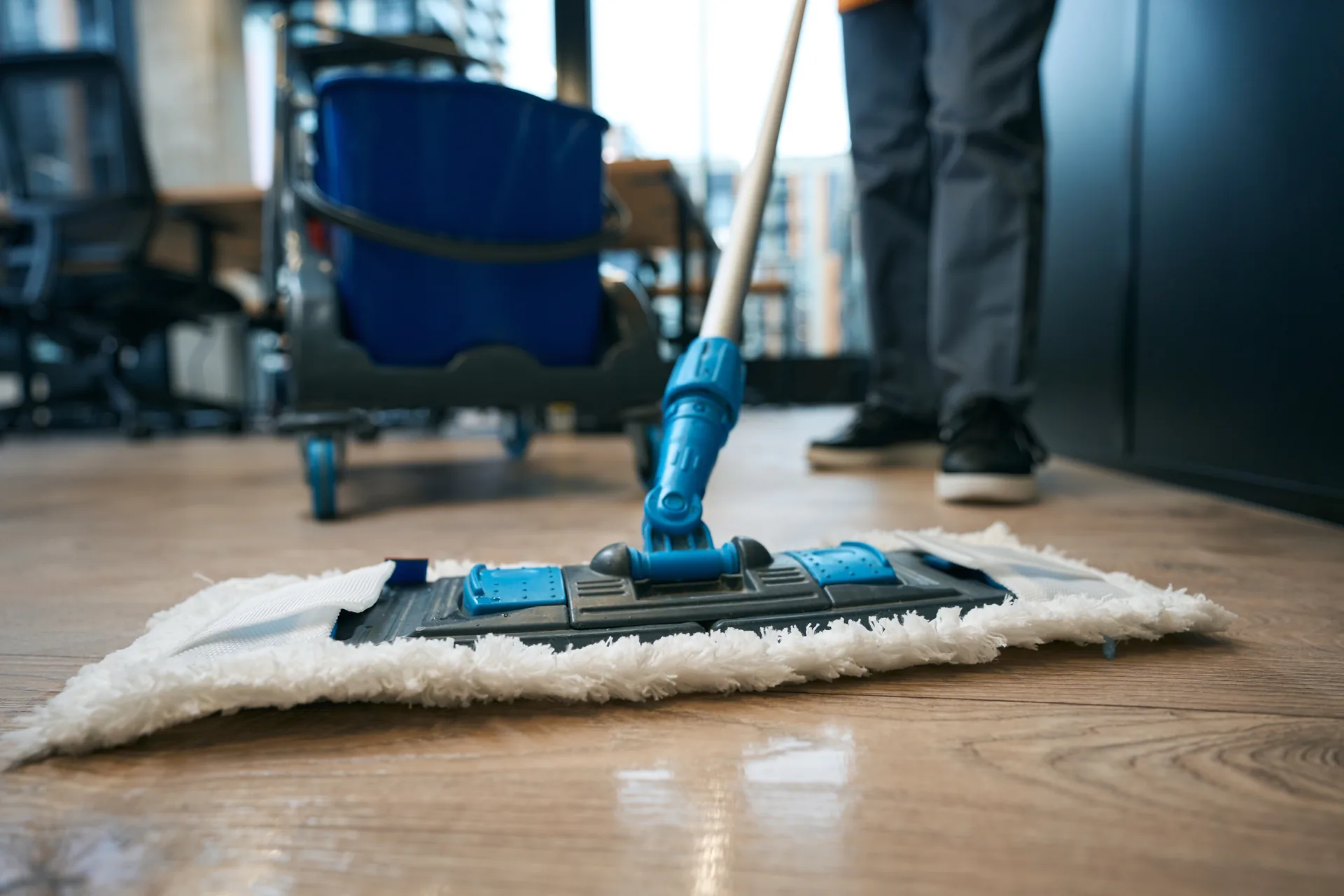 Cleaner mopping a polished office floor after hours
